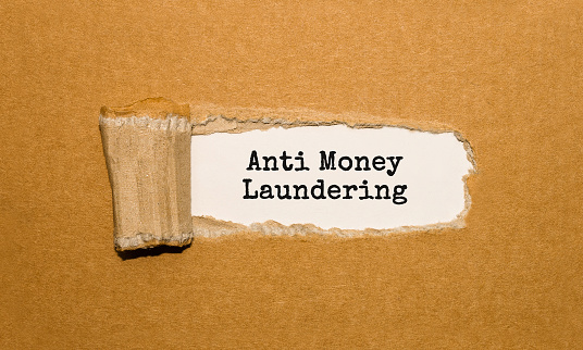 The text Anti Money Laundering appearing behind torn brown paper