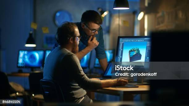 Two Male Game Developers Discuss Game Level Drawing One Uses Graphic Tablet They Work Late At Night In A Loft Office Stock Photo - Download Image Now