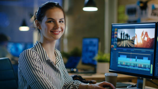 Female Video Editor Turns and Warmly Smiles into the Camera. Her Office is Modern and Creative Loft Studio. Female Video Editor Turns and Warmly Smiles into the Camera. Her Office is Modern and Creative Loft Studio. producer stock pictures, royalty-free photos & images