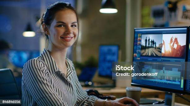 Female Video Editor Turns And Warmly Smiles Into The Camera Her Office Is Modern And Creative Loft Studio Stock Photo - Download Image Now