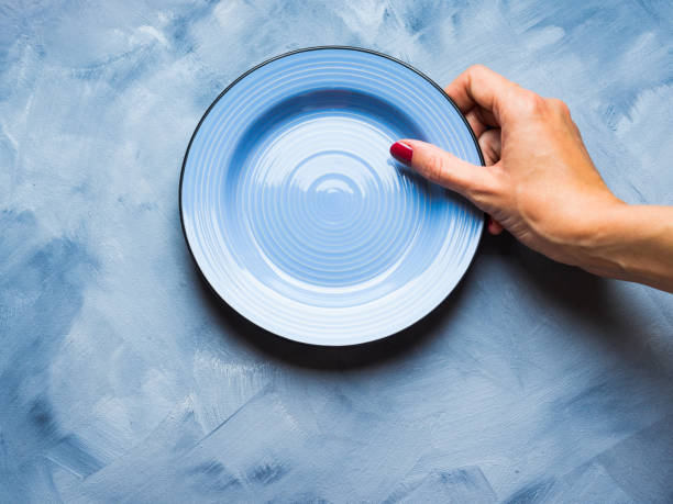 istock Blue background with plate and woman's hand 846860776