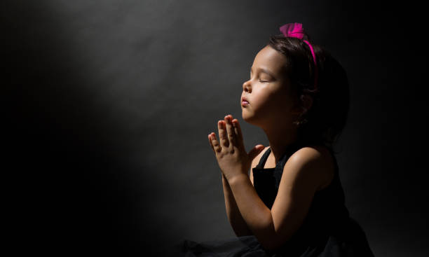 istock Little girl praying, isolated black background 846863756