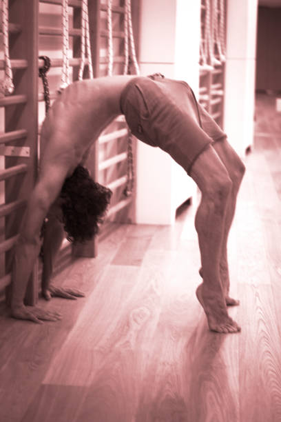 professeur de yoga fait backbend pont souplesse et résistance asana position formation ingym - yoga men bridge bending over backwards photos et images de collection