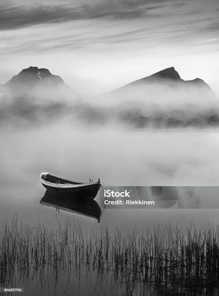 Very peaceful summer night with wooden boat and fog in Lofoten, Norway Black And White Stock Photo