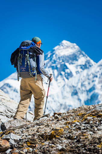 Mountaineer hiking along the rocky trail of the Renjo La below the iconic summit pyramid of Mt. Everest (8841m) deep in the Himalayan mountain wilderness of the Sagarmatha National Park, Nepal.