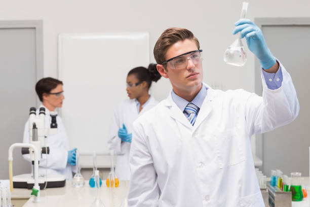 Scientist looking at white precipitate while colleagues talking together