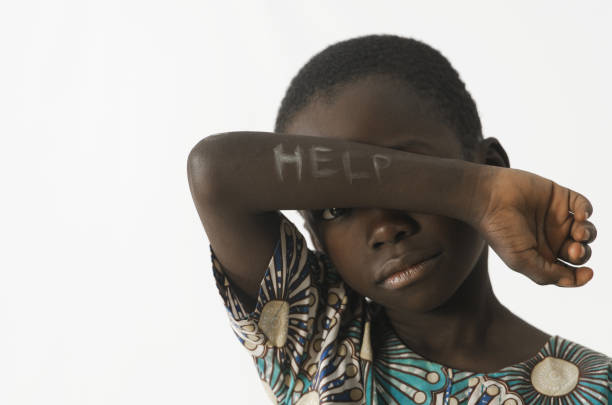 afrikaanse jongetje vraagt om hulp door die betrekking hebben op zijn gezicht met zijn arm, geïsoleerd op wit - afrika afrika stockfoto's en -beelden