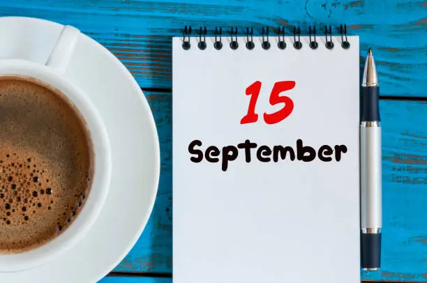 September 15th. Day 15 of month, hot coffee cup with loose-leaf calendar on accauntant workplace background. Autumn time. Empty space for text.