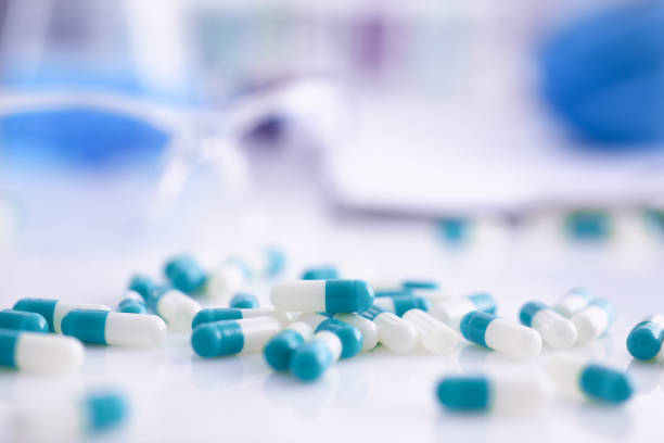 comprimidos espalharam sobre a mesa do laboratório farmacêutico - capsule close up medicine dose - fotografias e filmes do acervo