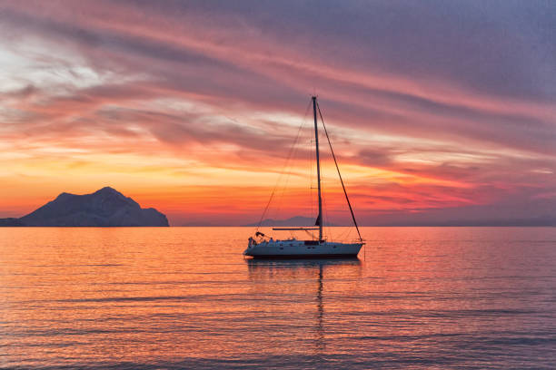 istock Sailboat sunset silhouette is a sailboat sailing along the water 846932020