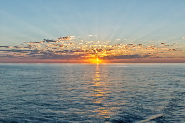 beautiful seascape with deep ocean waters and sunrise cloudscape, looking back towards one of the many Greek Islands