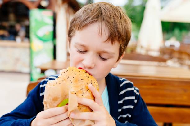 istock Hungry child eating burger outdoors. 846956438