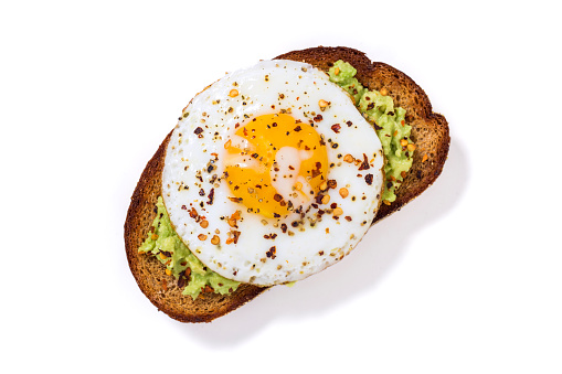 Avocado whole wheat toast on a white background with fried egg.