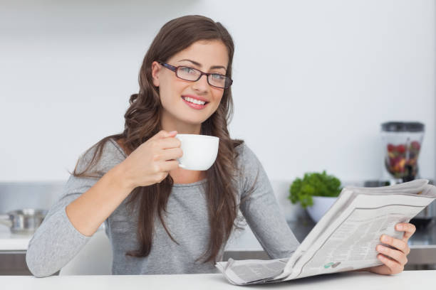 istock Woman holding a cup of coffee while reading a newspaper 846978952