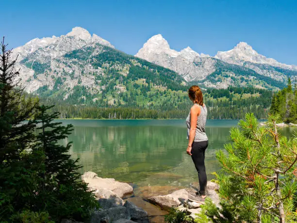 Photo of Young female hiker standing at lakeside of Jenny Lake at Grand Teton National Park, Wyoming, USA