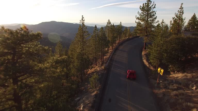 Aerial red sports car chase through forest