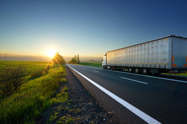 istock White truck driving on the road toward the setting sun 847005830