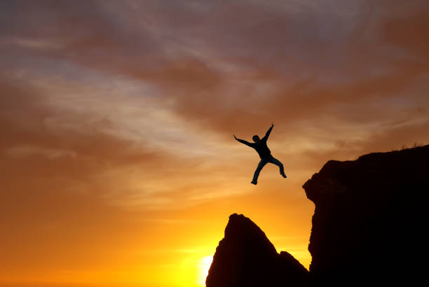 istock Jumping man against sunset sky background 847029940