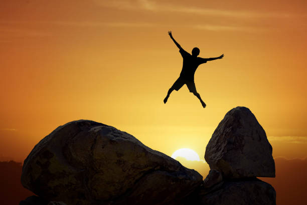 istock Man jumping against sunset sky background 847030020
