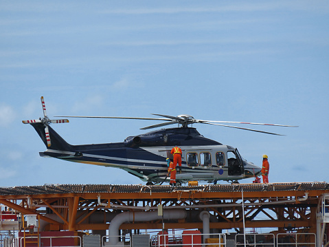 Helicopter or chopper land at oil and gas platform area for get and sent passenger from onshore hangar to offshore platform. Ground staff fill the gas tank( jet-A1 fuels) in helicopter.