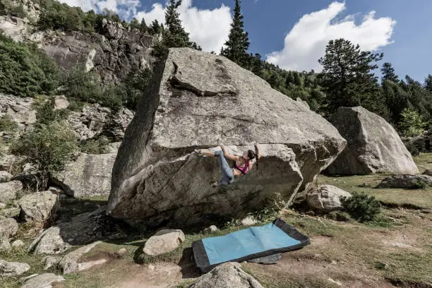 Woman practicing rock bouldering climbing in the Pyrenees mountains