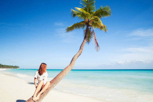 istock Girl sitting on a palm tree. Saona island beach 847032916