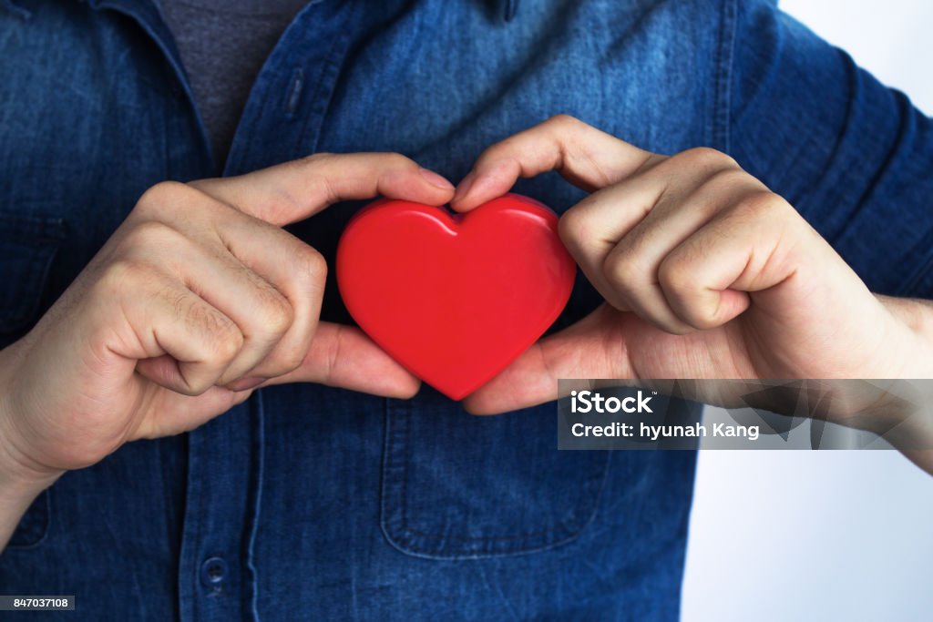 A young man has a red heart shape on his chest by hand.(World heart day,Valentine's day,Love) Heart Shape Stock Photo