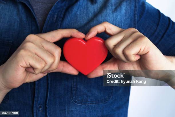 A Young Man Has A Red Heart Shape On His Chest By Hand Stock Photo - Download Image Now