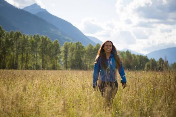 young indigenous canadian woman walking in a field - first nations imagens e fotografias de stock
