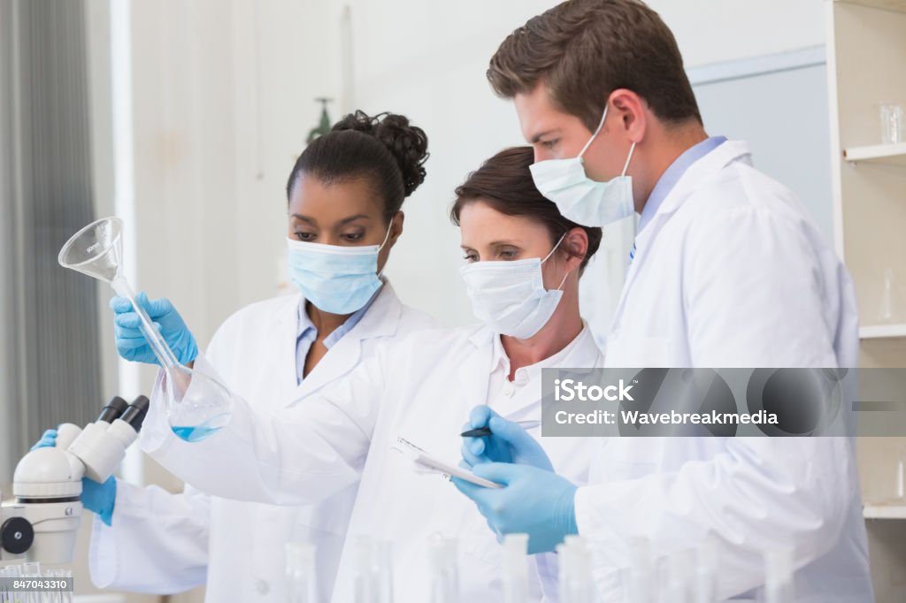 Scientists Comparing Notes Scientists Looking At Beaker And Taking Notes Stock Photo - Download ...