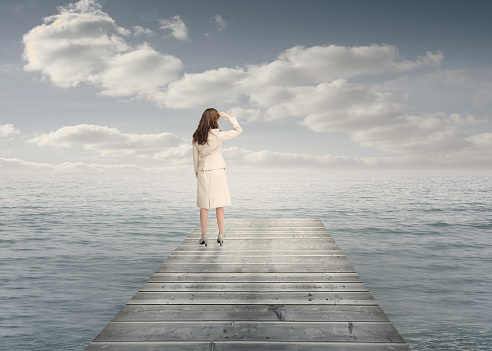 Businesswoman standing on a bridge and looking at the sea