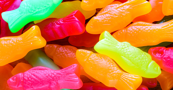Closeup gummy textured fish in red, pink, yellow, orange, and green.