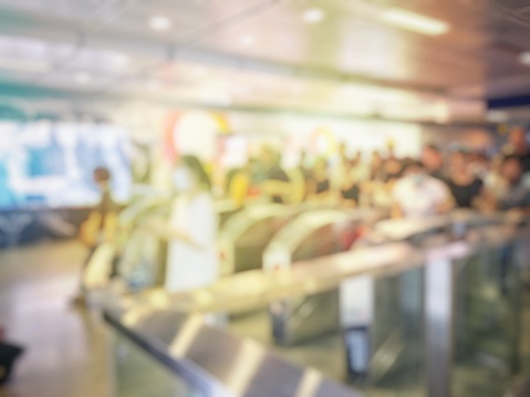 blurred image of passengers go through the subway train station ticket barriers.  Asian people waiting at boarding gate,  queue travel, tourism, business concept