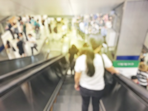 blurred image of business people, workers, many people left the train and go to work in the rush hour by subway, blurred background in subway. view from going down by escalator..