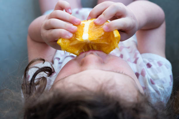istock Child eating orange from above 847060996