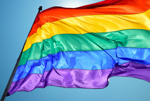 Rainbow flag on clear sky symbol of tolerance and acceptance Rainbow Flag consists of six stripes, with the colours red, orange, yellow, green, blue, and violet rainbow flag photos stock pictures, royalty-free photos & images