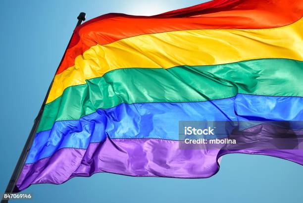 Rainbow Flag On Clear Sky Symbol Of Tolerance And Acceptance Stock Photo - Download Image Now