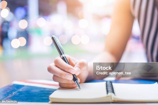 Photo libre de droit de Main De Femme Sur Un Cahier Décriture Avec Un Stylo Sur Un Bureau En Bois banque d'images et plus d'images libres de droit de Écriture manuscrite