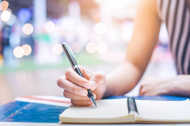 woman's hand writing on a notebook with a pen on a wooden desk. - old fashioned desk student book imagens e fotografias de stock