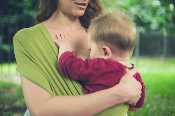 A young mother is breastfeeding her baby in the park
