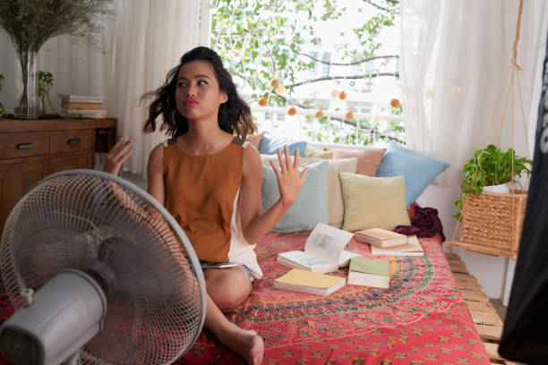 Too hot at home Sweating Asian girl cooling herself with big fan hot vietnamese women pictures stock pictures, royalty-free photos & images