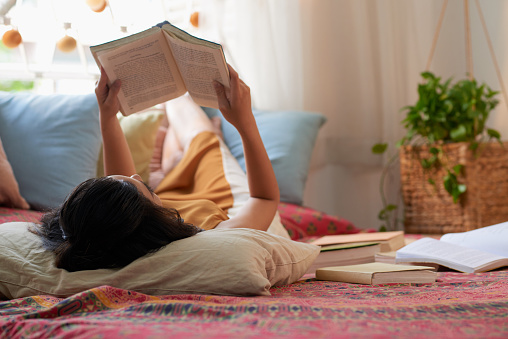 Woman enjoying her weekend lying in bed with a book