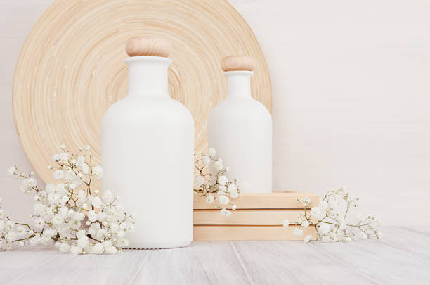 Blank white cosmetics bottles with small flowers on white wood board, copy space, mock up. Blank white cosmetics bottles with small flowers on white wood board, copy space, mock up. Soft elegant home decor for advertising, designers, branding identity, cover. makeup product photography stock pictures, royalty-free photos & images