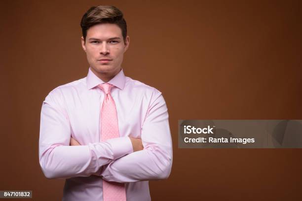 Studio Shot Of Young Handsome Businessman Wearing Pink Shirt With Pink Necktie Against Colored Background Stock Photo - Download Image Now