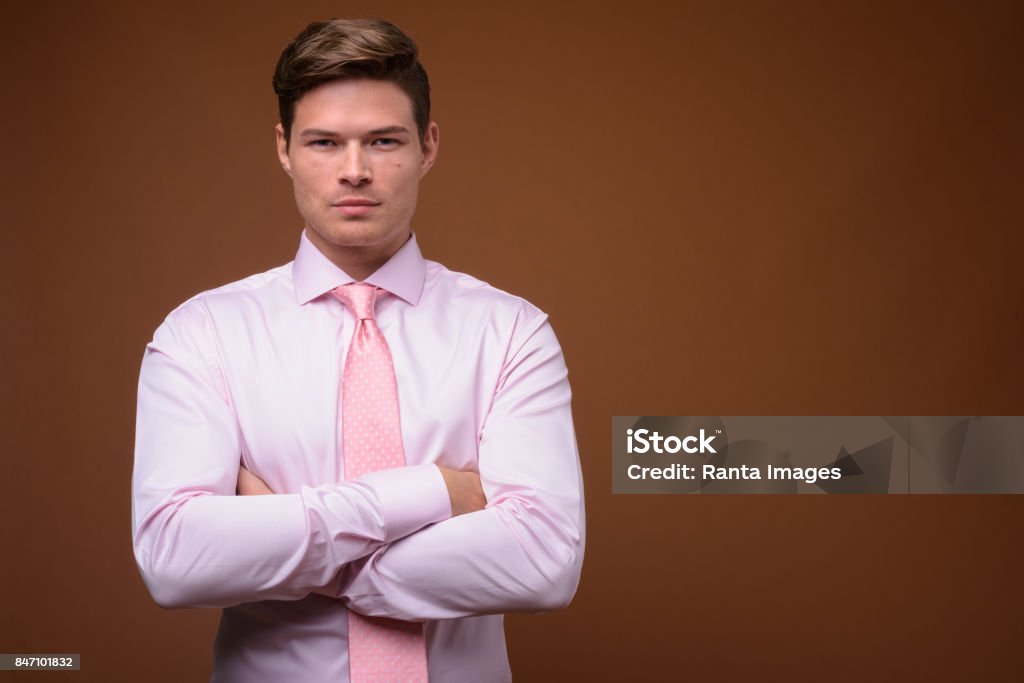 Foto de estúdio do jovem empresário bonito vestindo uma camisa rosa com gravata rosa contra o fundo colorido - Foto de stock de 20 Anos royalty-free