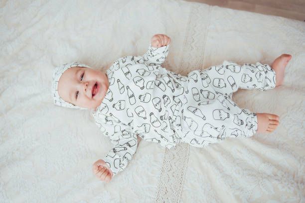 nouveau-né, vêtu d’un costume sur un lit douillet dans le studio. - newborn little girls baby lying down photos et images de collection