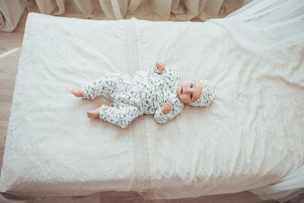 nouveau-né, vêtu d’un costume sur un lit douillet dans le studio. - newborn little girls baby lying down photos et images de collection