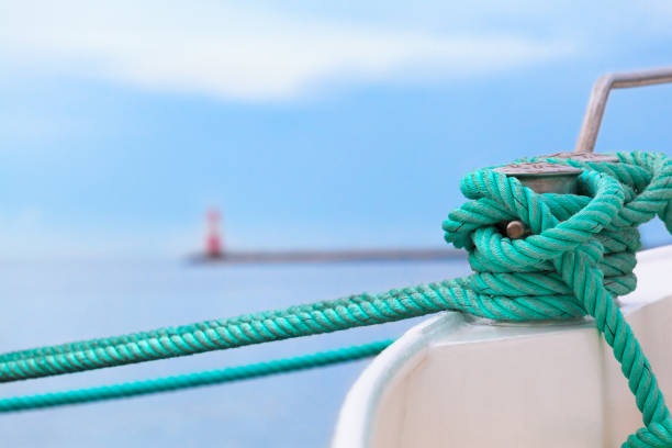 Before put out to Sea Voyage Green rope fix boat with knot at bollard in harbor - pier, lighthouse, open sea at background (copy space) rostock photos stock pictures, royalty-free photos & images