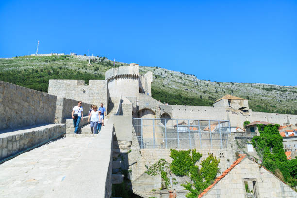 Panoramic view at Minceta Tower in Dubrovnik, Croatia Tourists walking on top of old town's walls while behind them theres' Minceta tower - Game of Thrones filming location in Dubrovnik, Croatia fort minceta dubrovnik stock pictures, royalty-free photos & images