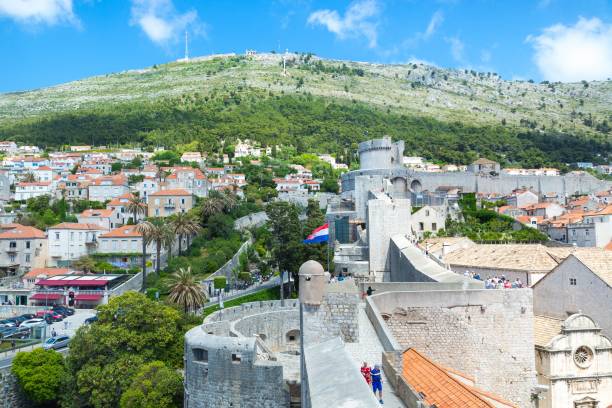 Panoramic view at Dubrovnik old town, Croatia and Minceta tower Tourists walking on top of old town's walls while behind them theres' Minceta tower - Game of Thrones filming location in Dubrovnik, Croatia fort minceta dubrovnik stock pictures, royalty-free photos & images